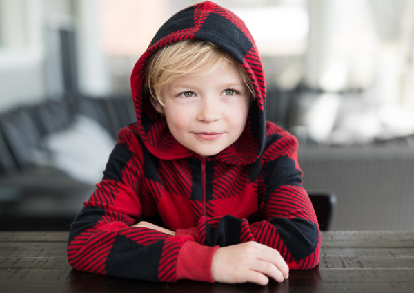 Portrait of blonde little boy (7) with messy hair in the morning at the kitchen table.